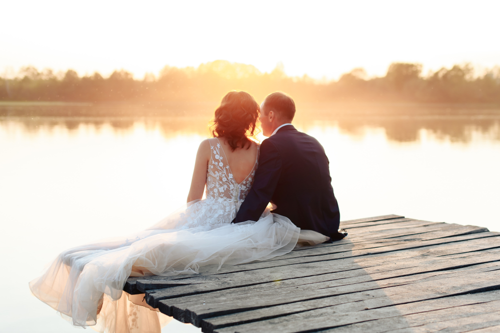 bride and groom resting on the pier at sunset